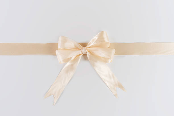 istock A light gold ribbon is tied in a bow and arranged horizontally, placed centrally on a plain white background. 2198205232