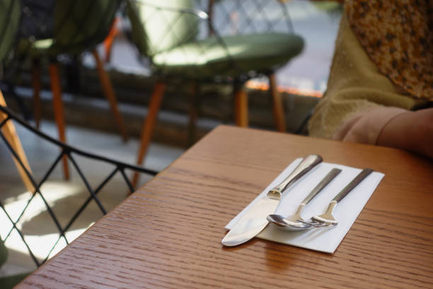 Close up on outdoor dining table with drinking glass, fork, knife and napkin on a restaurant patio downtown Old Quebec during summer day
