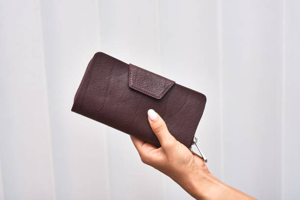 istock Hand holding elegant maroon wallet with clasp, showcasing stylish accessory, perfect for fashion-conscious individuals, wallet concept 2198213687