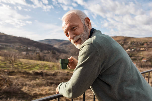 istock Senior Man Relaxing with Coffee at Sunrise Looking At Camera 2198214140