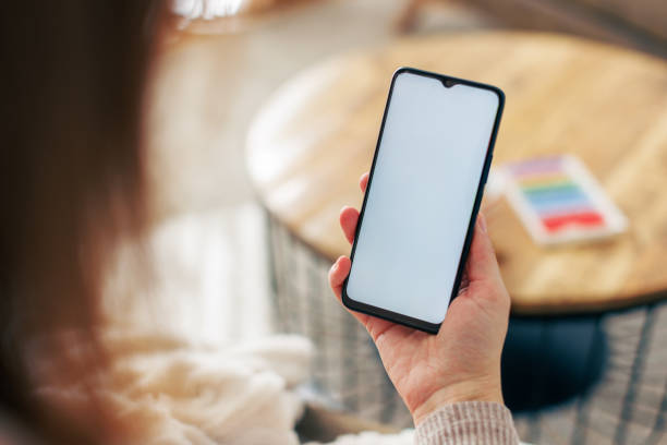 istock Woman Holding Smartphone at Home with Blank Screen 2198214149