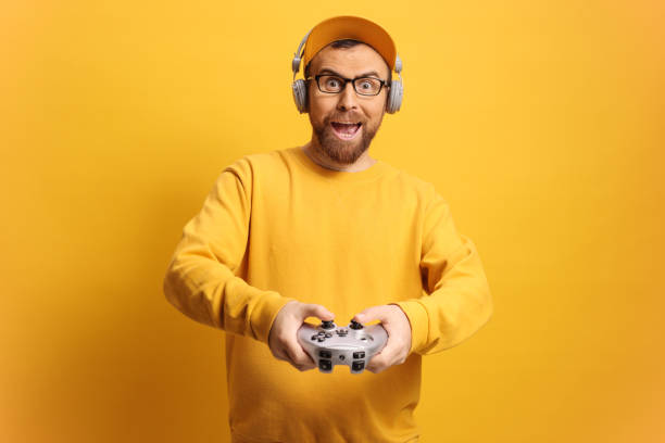 Man with headphones and joystick playing video games against a yellow background