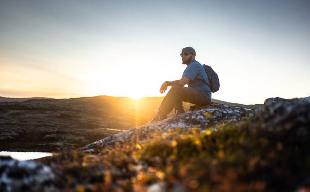 istock Adventurer sitting on a rock during a stunning sunset in the wilderness 2198220203