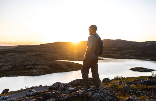 istock Hiker Standing on Rocks Overlooking Scenic Lake at Sunset 2198220273