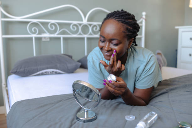 istock Woman applying skincare while looking at a mirror in a comfortable bedroom 2198220316