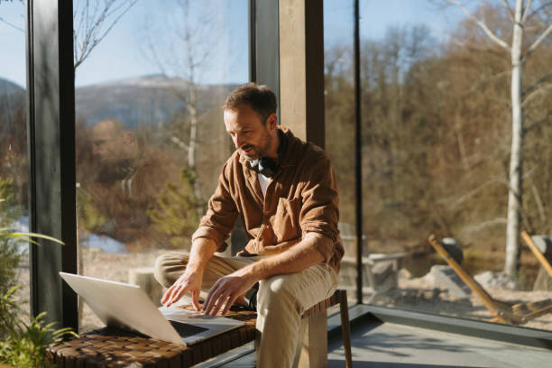 istock Man using a laptop in a cabin house 2198220817
