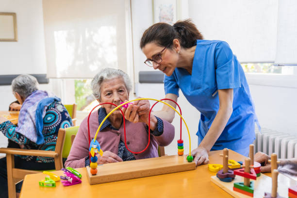 istock Caregiver assisting senior woman with therapy activity 2198222048