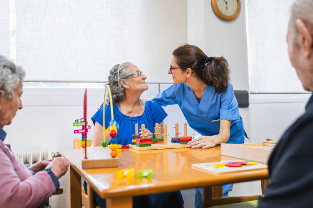 istock Nurse supporting elderly woman during sensory play in nursing home 2198222127