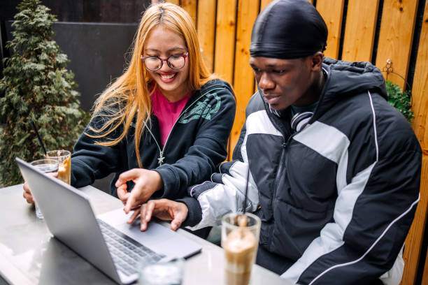 istock Friends enjoying having coffee at sidewalk cafe while looking at laptop 2198223838