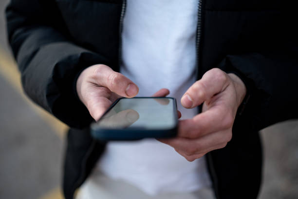 istock a guy is typing a message on a phone in the city 2198224203