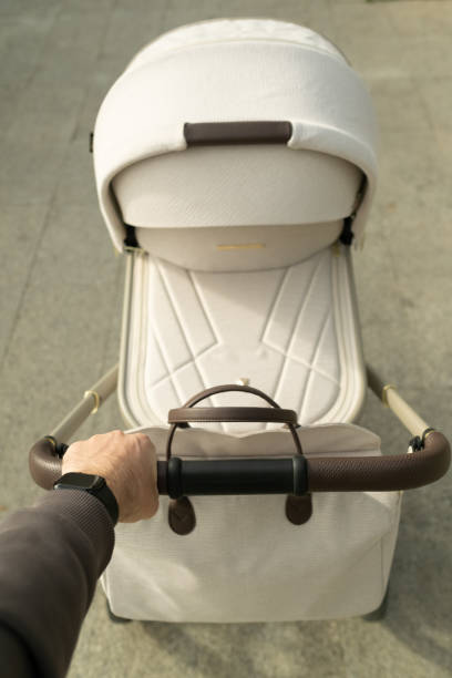 istock Man’s hand holding the handle of the baby stroller from above 2198225493