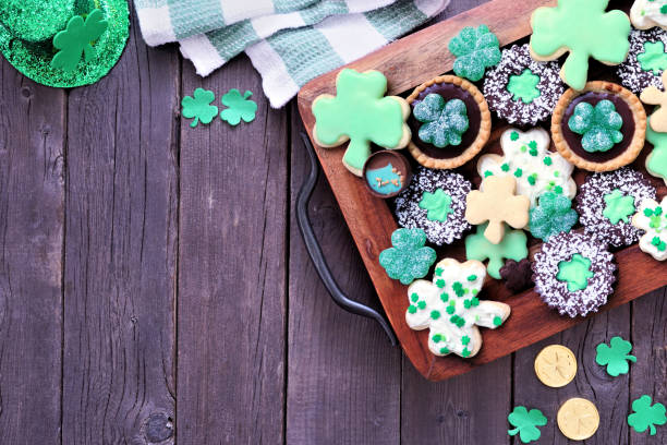 istock St Patricks Day shamrock dessert board. Green cookies and sweets. Top down view table scene over a rustic wood background with copy space. 2198229719