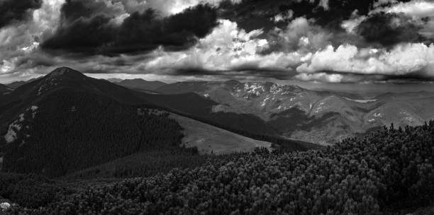 The view of the dense forest surrounding the valley gives a sense of seclusion and immersion in nature. The clouds cast a light shadow, softening the sunlight and adding depth to the scene.