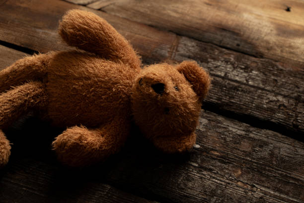 istock Brown soft baby teddy bear lying abandoned on the floor 2198233871