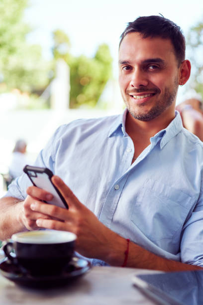 istock Young businessman using phone and drinking coffee at outdoor cafe 2198237932