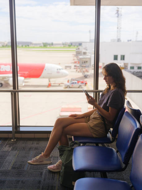istock Woman using smartphone while waiting in airport departure area 2198249126