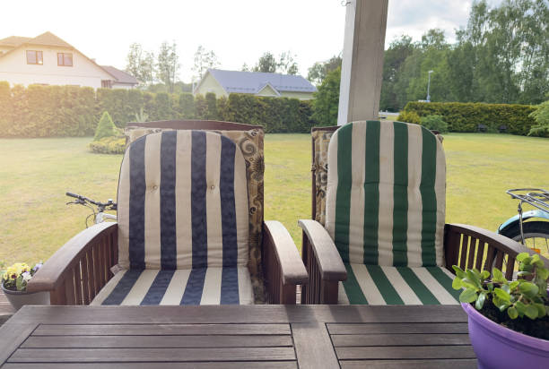 Flat net balcony seat or bed with blue striped cushions on a balcony with a view of green tropical nature blurred in the background