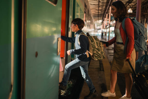 istock Son and mother with suitcases boarding the train for the journey 2198252463
