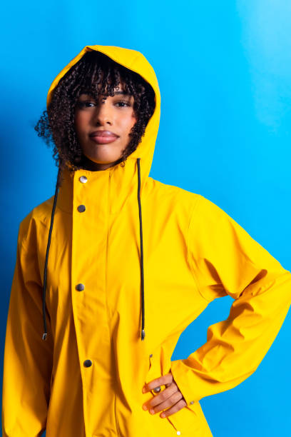 istock Young woman wearing a yellow raincoat posing with hand on hip 2198253696