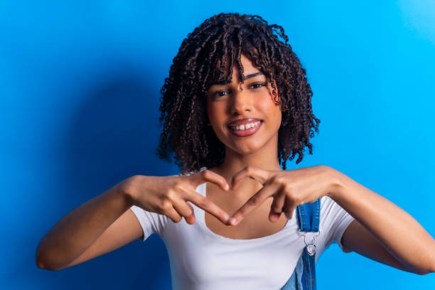istock Young woman making heart shape with hands on blue background 2198253776