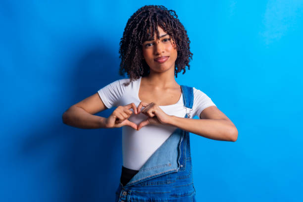 istock Young woman making heart shape with hands on blue background 2198253838