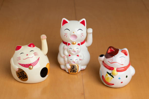 istock Three white maneki neko cat figures with their paws up for good luck 2198264936