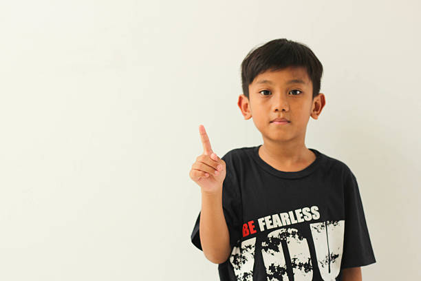 Little boy looking at camera and snapping fingers. Smiling little boy wearing casual clothing and standing in front of colored background. Horizontal composition. Image developed from Raw format.