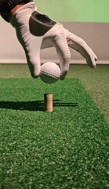 istock Hand placing a golf ball on a tee during an indoor practice session at a golf facility concept 2198294306