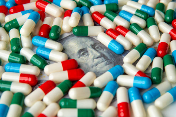 istock A close-up image of colorful capsules scattered on a US dollar bill. 2198294932