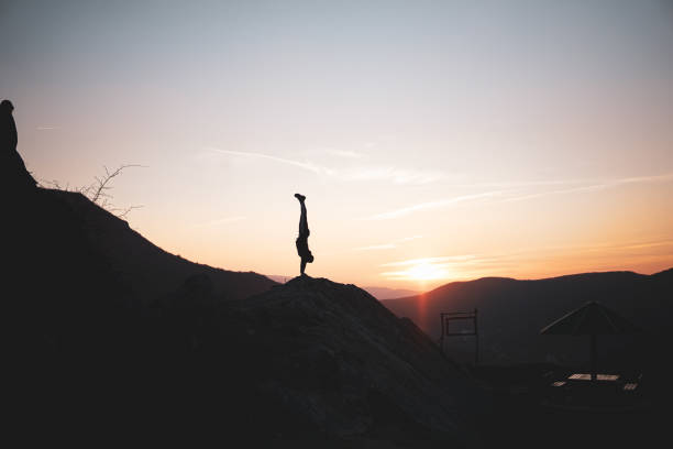 istock Man doing a handstand on high viewpoint balancing on mountain edge. Silhouette. 2198302426