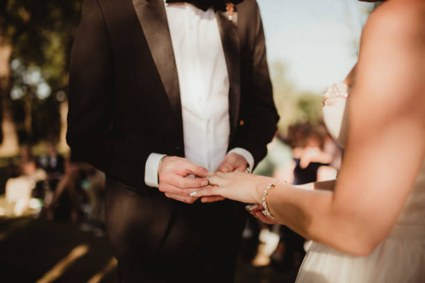 Close up of couple saying wedding vows and exchanging rings outdoors