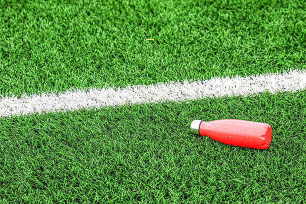 Red aluminum bottle on a field of artificial grass. Hydration. Sport.