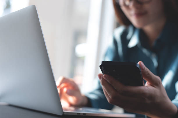 istock Young smart business woman using mobile phone, surfing the internet during working on laptop computer at modern office. Casual business woman online working from home office, connecting wifi, online shopping 2198309070