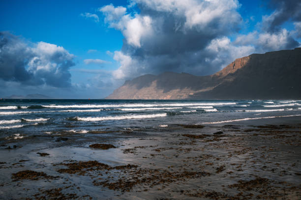 istock Volcanic Pebble Beach in Lanzarote: Rugged Coastline and Ocean Waves 2198312505