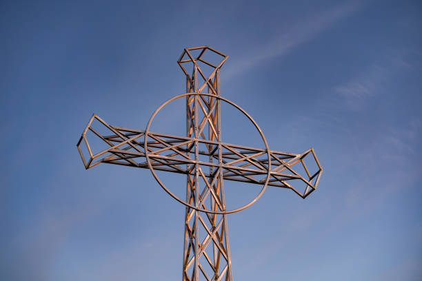 A symbolic cross on Tarnica peak during a cold November sunset, with a scenic view of the Bieszczady Mountains and a cloudy blue sky.