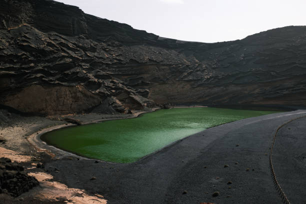 A stunning volcanic landscape in Lanzarote, Canary Islands, featuring black lava rocks and reddish mountains. The arid and wild scenery resembles a lunar environment, a testament to the eruptions that shaped the island. A unique place where nature tells its story through geological formations and earth tones