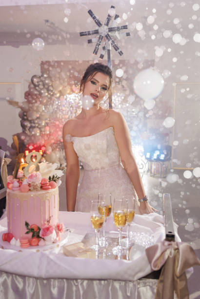 Beautiful girl in while dress dancing and singing among bubbles and birthday cake at 18th birthday party