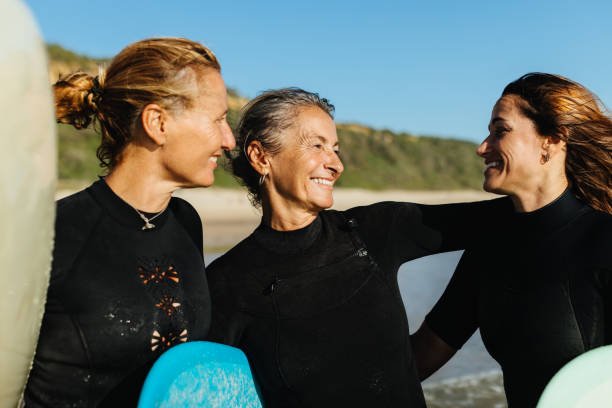 istock Three friends enjoying surfing together in wetsuits on a sunny beach 2198315625