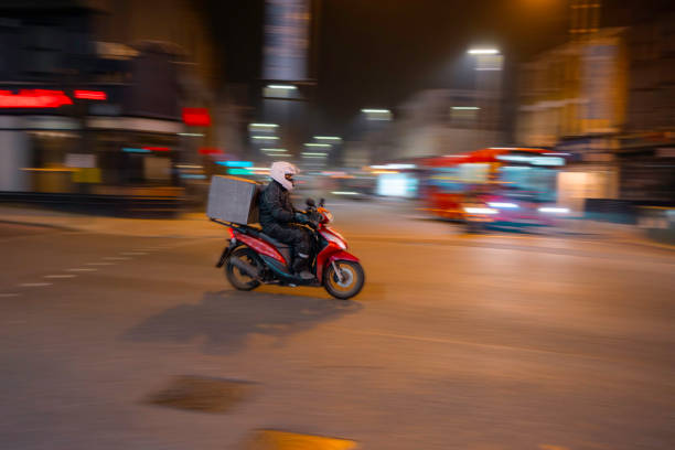Man on a scooter driving past the camera, long exposure technique
