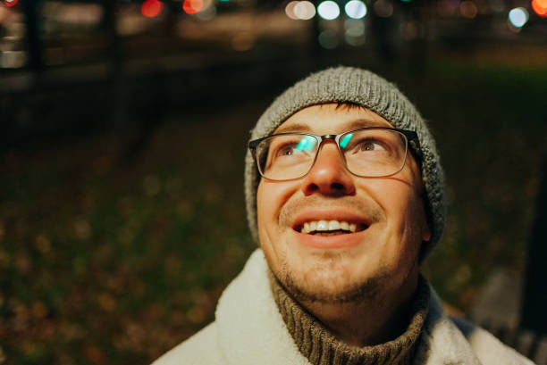 istock Smiling man wearing glasses and beanie looking up at night 2198318562