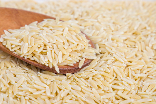 istock uncooked orzo pasta in wooden spoon, rice shaped pasta, selective focus 2198318717