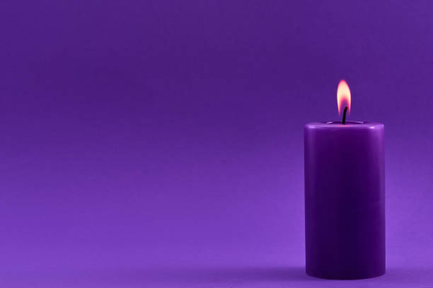istock Purple Candle. A single purple candle burning with a soft flame 2198319483