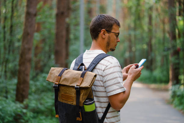 istock Man Hiking in Forest with Backpack, Checking Smartphone for Navigation or Messages 2198319754