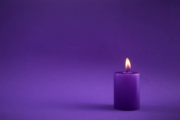 istock Purple Candle. A single purple candle burning with a soft flame 2198319886