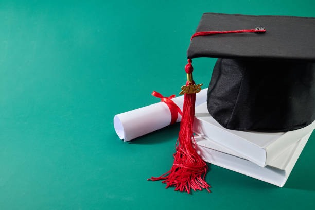 istock Graduation Celebration. A graduation cap with a red tassel and a diploma 2198319970