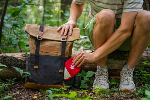 Hiker packing first aid kit into backpack during outdoor adventure
