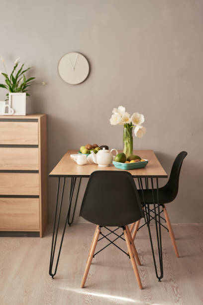 istock Loft style dining room. Dining table with chairs. Mock up interior photo. Black chairs at dining table in bright dining room with flowers. Kitchen island and table in contemporary apartment interior 2198321705