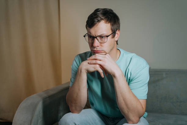 Pensive man contemplating life's challenges on sofa at home