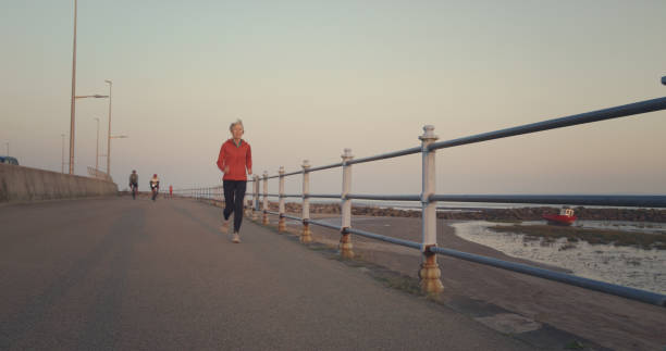 Senior woman jogging on the promenade at the seaside town of Morecambe, Lancashire, England.