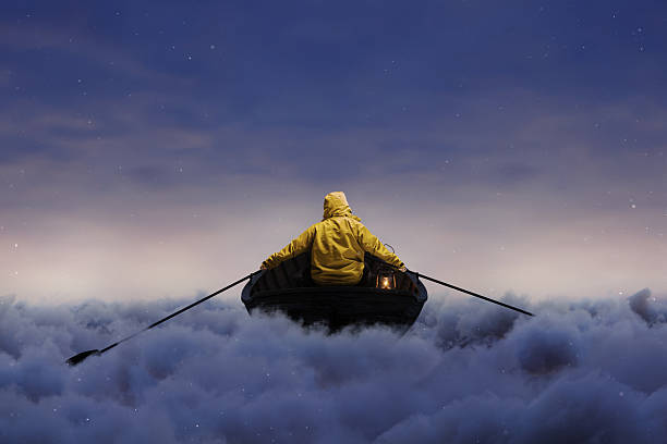 digital composition of a lonely rower on an old boat over blue clouds